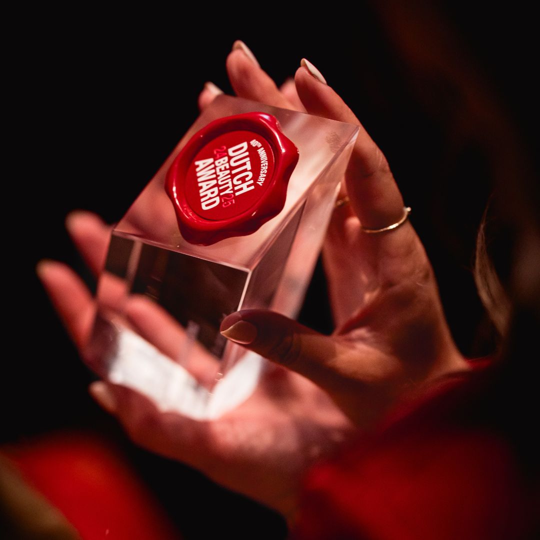 Clear crystal award with red seal held by hands against a dark background